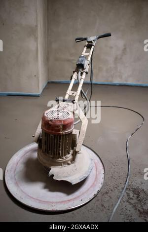 Professionelle Maschine zum Aufführen und Polieren von Sand und Zement Estrichboden auf der Baustelle einer neuen zweistöckigen Wohnung. Sand und Zement Stockfoto