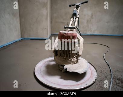 Professionelle Maschine zum Aufführen und Polieren von Sand und Zement Estrichboden auf der Baustelle einer neuen zweistöckigen Wohnung. Sand und Zement Stockfoto
