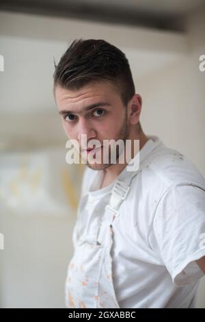 Portrait von Fachangestellten mit schmutziger Uniform in der Wohnung, die im Bau ist, Umbau, Renovierung, Erweiterung, Wiederherstellung, Überholung und Stockfoto