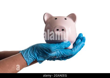 Arzt oder Pfleger, die chirurgische Handschuhe tragen, die Piggy Bank auf Weiß isoliert. Stockfoto