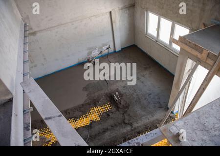 Professionelle Maschine zum Aufführen und Polieren von Sand und Zement Estrichboden auf der Baustelle einer neuen zweistöckigen Wohnung. Sand und Zement Stockfoto