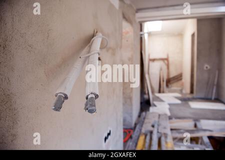 Buchsenleiste mit Kabeln in einer Wand. Kabelhintergrund: Elektrische Drähte, die aus der Öffnung der Steckdosen an der Wand herausragenbleiben. Neue elektrische Version Stockfoto