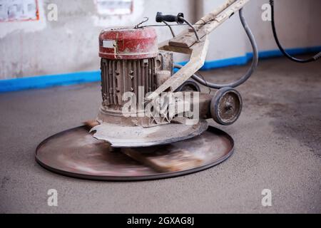 Professionelle Maschine zum Aufführen und Polieren von Sand und Zement Estrichboden auf der Baustelle einer neuen zweistöckigen Wohnung. Sand und Zement Stockfoto