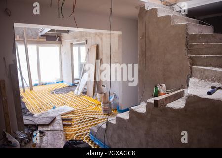 Gelbe Fußbodenheizung mit weißen Polyethylenrohren auf der Baustelle der neuen zweistöckigen Wohnung Stockfoto