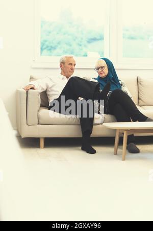 Porträt eines modernen muslimischen älteren Paares, das vor dem iftar-Abendessen während eines ramadan-Festes zu Hause auf dem Sofa sitzt Stockfoto