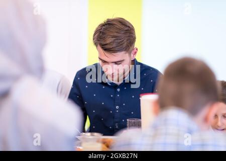 Junger, moderner muslimischer Mann genießt das iftar-Abendessen zusammen mit einer multiethnischen Familie während eines ramadan-Festes zu Hause Stockfoto