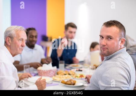 Junger, moderner muslimischer Mann genießt das iftar-Abendessen zusammen mit einer multiethnischen Familie während eines ramadan-Festes zu Hause Stockfoto