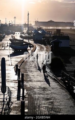 Brighton UK 2. Oktober 2021 - Spaziergänger am frühen Morgen an der Küste von Brighton, wenn die Sonne nach einer Nacht mit starkem Regen und starken Winden im Südosten Großbritanniens aufgeht : Credit Simon Dack / Alamy Live News Stockfoto