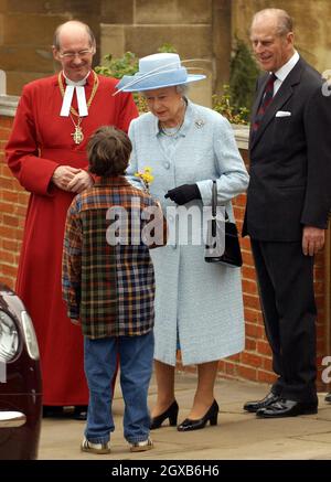 Die britische Königin Elizabeth II. Nimmt am heutigen Sonntag, 27. März 2005, eine schicke Frühlingsblume von der achtjährigen Zachary McCarthy-Fox entgegen, als sie den Ostersonntagsgottesdienst in der St. Georges Chapel, Windsor Castle, verlässt. Die Königin wird von Prinz Philip, dem Herzog von Edinburgh, und Bischof David Conner, dem Dekan von Windsor (links), begleitet. Anwar Hussein/allactiondigital.com Stockfoto