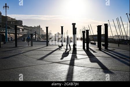 Brighton UK 2. Oktober 2021 - Spaziergänger an der Küste von Brighton an der Golden Spiral, wenn die Sonne nach einer Nacht mit heftigem Regen und starken Winden im Südosten Großbritanniens aufgeht : Credit Simon Dack / Alamy Live News Stockfoto