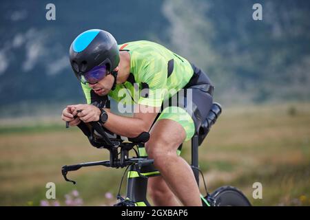 triathlon-Athlet auf einem professionellen Rennrad beim Training auf kurviger Landstraße Stockfoto