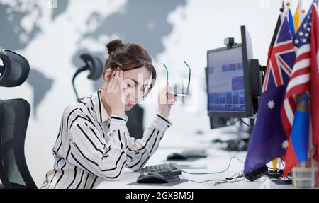 Müde Casual Business Frau, die eine Pause während der Arbeit auf Desktop-Computer in modernen offenen Plan Startup-Büro Innendeadline Stress-Konzept Stockfoto