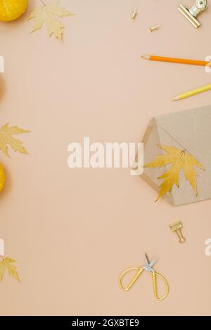 Kreative Herbst flache Komposition auf beigem Hintergrund mit gelben Blättern und Kürbissen, Stift, Schere, Büroklammern und Bastelhülle mit weißem pa Stockfoto