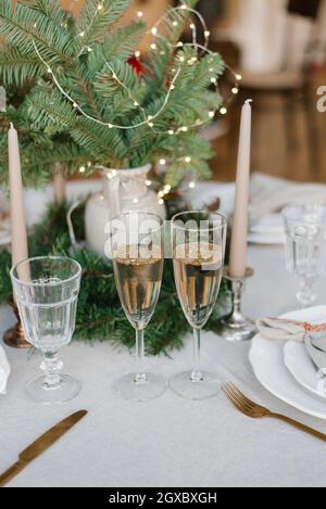 Weihnachtliche Einrichtung des Festtisches: Zwei Gläser Champagner, serviert Abendessen für ein verliebtes Paar Stockfoto