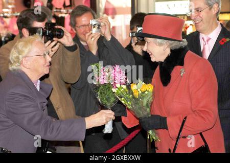 Queen Elizabeth II wird am 3. November 2006 bei ihrem Besuch der County Mall in Crawley, West Sussex, mit einem Blumenstrauß überreicht. Die Königin hat ihre ursprünglichen Pläne für den Besuch aufgrund der anhaltenden Rückenschmerzen zurückgeschraubt. Anwar Hussein/EMPICS Entertainment Stockfoto