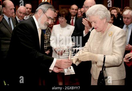 Königin Elizabeth II. Erhält vom Oberrabbiner Sir Jonathan Sacks einen chanukka-Kerzenständer, während sie an einem Empfang im St. James's Palace in London teilnimmt, um den 350. Jahrestag der Wiedergründung der jüdischen Gemeinde in Großbritannien am 28. November 2006 zu begehen. Anwar Hussein/EMPICS Entertainment Stockfoto