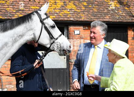 Königin Elizabeth II füttert ein Pferd mit einer Karotte, beobachtet von Trainer Paul Nicholls, während eines Besuchs im Manor Farm Stables in Ditcheat, Somerset, am 28. März 2019. Stockfoto