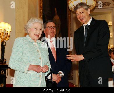 Königin Elizabeth II trifft am 15. Februar 2007 den Vorsitzenden von Arsenal, Peter Hill-Wood, und den Manager Arsene Wenger (rechts) im Buckingham Palace in London. Stockfoto