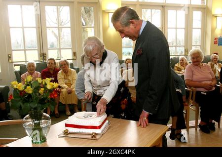 Prinz Charles, Prinz von Wales, sieht an, wie die 105-jährige Hettie Hyndman am 23. März in Whiteley Village, in Walton-on-Thames, Surrey, ihren Geburtstagskuchen schneidet. 2007. Der Prinz besuchte die Altersgruppe aufgrund seiner Rolle als Schirmherr des Almshouse-Vereins. Stockfoto