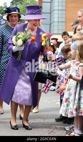 Königin Elizabeth II. Erhält Blumen von Kindern nach einem Gedenkgottesdienst zum Gedenken an den 25. Jahrestag des Falklands-Konflikts in der Falkland Islands Memorial Chapel im Pangbourne College, in der Grafschaft von Bekshire. Stockfoto