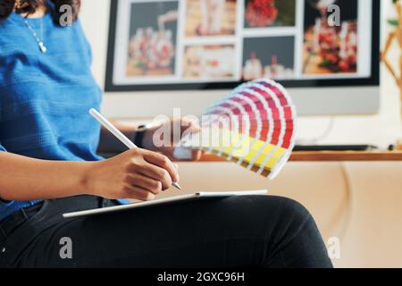 Nahaufnahme einer nicht erkennbaren Frau, die mit einem Digitalisierer zeichnet, während sie Farbe für ein Designprojekt im Büro ausnimmt Stockfoto
