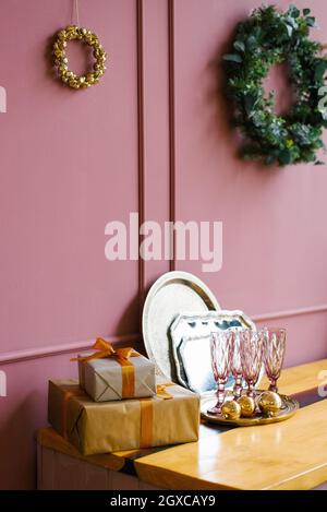 Rosa Gläser, Geschenkboxen, Weihnachtsbaumkranz, Metalltabletts in der rosa Küche. Weihnachtsdekor im Haus Stockfoto