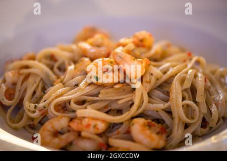Spaghetti aglio e olio mit Garnelen. Gesundes, einfaches und leckeres Nudelgericht. Nahaufnahme der Platte. Stockfoto