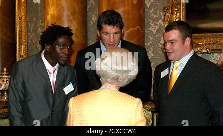 Queen Elizabeth II trifft Rugbyspieler (von links nach rechts) Paul Sackey, Simon Shaw und Matt Stevens bei einem Empfang für Commonwealth-Afrikaner im Buckingham Palace, London. Stockfoto