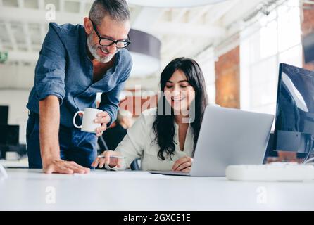 Zwei glückliche Kollegen, die im Büro an einem neuen Projekt mitarbeiten. Reifer Geschäftsmann, der sich mit seiner Kollegin in einem modernen Büro zusammenschließen kann. Zwei Säule Stockfoto