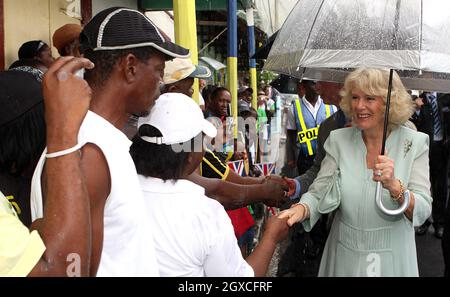 Camilla, Herzogin von Cornwall, schützt sich vor dem Regen unter einem Regenschirm, als sie sich bei ihrer Ankunft in Soufriere, St. Lucia, am 7. März 2008 mit den Einheimischen in die Hände schüttelt. Stockfoto