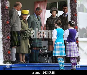 Prinz Philip, Herzog von Edinburgh, Königin Elizabeth II., Prinz Charles, Prinz von Wales und Prinzessin Anne, Prinzessin Royal, werden von Mädchen bei den Braemar Highland Games 2009 am 5. September 2009 in Braemar, Schottland, begrüßt. Das Braemar Gathering ist weltberühmt, und Tausende von Besuchern kommen jedes Jahr in das kleine schottische Dorf, um sich die Spiele anzusehen, eine schottische Tradition, die Jahrhunderte zurückreicht. Stockfoto