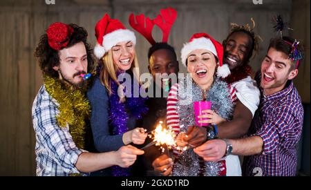 Multiethnische Gruppe junger happy and Business Leute Beleuchtung eine Wunderkerze und Spaß beim Silvester feiern in der betonwand an Stockfoto