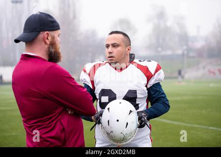 Young Professional football player diskutieren Strategie gemeinsam mit Trainer während der Ausbildung übereinstimmen, der auf dem Stadion Feld Stockfoto