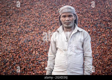 INDIEN, BANGLADESCH - 7. DEZEMBER 2015: Ethnischer indischer Mann in schmutziger Kleidung, der mit einem Steinhaufen auf dem Hintergrund eines Backsteinkis auf die Kamera schaut Stockfoto