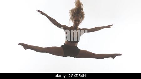 Junge schöne weibliche sportliche Tänzerin in schwarzen Strumpfhosen Durchführung modernen Stil Ballett machen akrobatische Elemente weibliche Balletttänzerin in Kunst performant Stockfoto