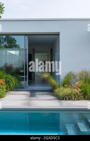 Schwimmbad im Hof der modernen weißen Villa mit Glastür an sonnigen Tag Stockfoto