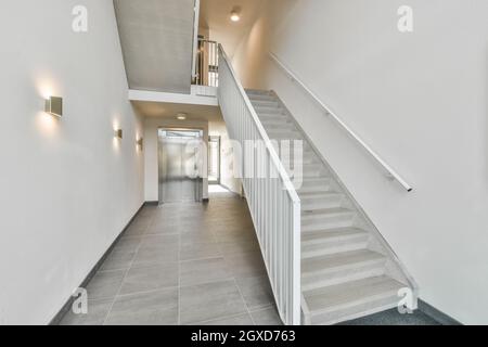 Modernes Interieur des geräumigen Flurs mit Treppe und Aufzug mit Metalltüren in einem modernen Wohngebäude Stockfoto