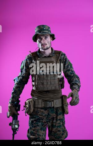 American Marine Corps Special Operations Modern Warfare Soldat mit Feuer arm Waffe und schützenden Armee taktische Ausrüstung bereit für den Kampf auf Rosa hinterg Stockfoto