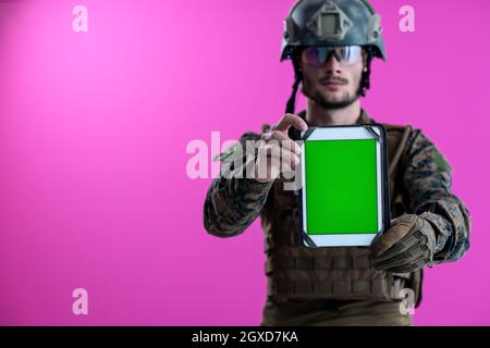 Armee Soldat mit einem Tablet-PC mit einem leeren Bildschirm grün auf rosa Hintergrund isoliert Stockfoto