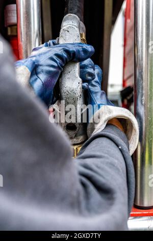 Lippstadt, Deutschland. Oktober 2021. Ein Mitarbeiter zieht den Schlauch für die Heizöllieferung an einen Kunden aus dem Tankwagen. Die Verbraucher können aufgrund der hohen weltweiten Nachfrage nach Rohöl in diesem Jahr mit einem starken Anstieg der Heizkosten rechnen. Noch teurer wird es 2021 in Häusern mit Ölheizung, wo die Kosten um 44 Prozent steigen sollen - nach einem Rückgang um 27 Prozent im Vorjahr. Kredit: David Inderlied/dpa/Alamy Live Nachrichten Stockfoto