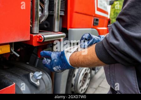 Lippstadt, Deutschland. Oktober 2021. Ein Mitarbeiter zieht seine Handschuhe an, um einem Kunden Heizöl zu liefern. Die Verbraucher können aufgrund der hohen weltweiten Nachfrage nach Rohöl in diesem Jahr mit einem starken Anstieg der Heizkosten rechnen. Noch teurer wird es 2021 in Häusern mit Ölheizung, wo die Kosten um 44 Prozent steigen sollen - nach einem Rückgang um 27 Prozent im Vorjahr. Kredit: David Inderlied/dpa/Alamy Live Nachrichten Stockfoto