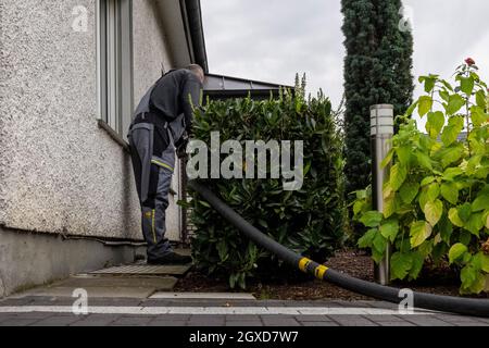 Lippstadt, Deutschland. Oktober 2021. Ein Mitarbeiter legt den Schlauch für die Heizöllieferung bis zum Hausanschluss. Die Verbraucher können aufgrund der hohen weltweiten Nachfrage nach Rohöl in diesem Jahr mit einem starken Anstieg der Heizkosten rechnen. Noch teurer wird es 2021 in Häusern mit Ölheizung, wo die Kosten um 44 Prozent steigen sollen - nach einem Rückgang um 27 Prozent im Vorjahr. Kredit: David Inderlied/dpa/Alamy Live Nachrichten Stockfoto