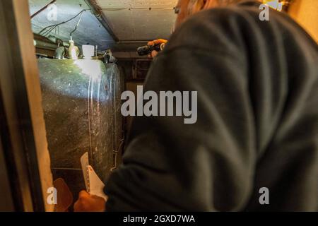 Lippstadt, Deutschland. Oktober 2021. Ein Mitarbeiter überprüft die Tanks im Keller eines Kunden, bevor er Heizöl liefert. Die Verbraucher können aufgrund der hohen weltweiten Nachfrage nach Rohöl in diesem Jahr mit einem starken Anstieg der Heizkosten rechnen. Noch teurer wird es 2021 in Häusern mit Ölheizung, wo die Kosten um 44 Prozent steigen sollen - nach einem Rückgang um 27 Prozent im Vorjahr. Kredit: David Inderlied/dpa/Alamy Live Nachrichten Stockfoto