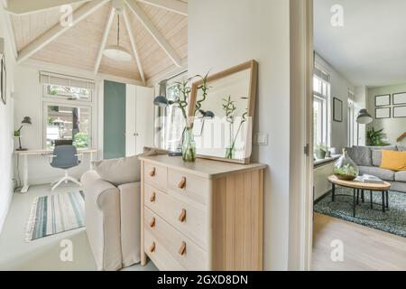 Interieur eines modernen Apartments im skandinavischen Stil mit Holzmöbeln und weißen Möbeln tagsüber Stockfoto