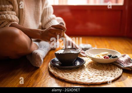 Durch Zaunloch Ansicht von jungen froh afroamerikanischen Männchen Mit Armbanduhr, die auf dem Handy spricht, während sie in die Cafeteria hinunterblickt Tabelle Stockfoto