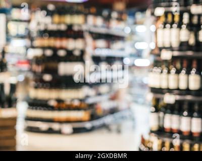 Abstrakt verschwommener Supermarkt bunte Regale mit Alkohol, Weinflaschen als Hintergrund Stockfoto