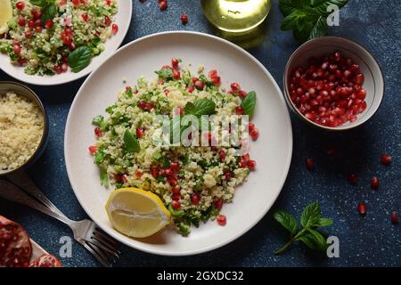 Gesunder Salat mit Couscous, frischer Minze, Gurke, Granatapfel, Zitrone und Olivenöl. Östliche Küche. Veganes Lebensmittelkonzept. Traditionelle israelische Küche Stockfoto