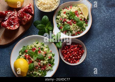 Gesunder Salat mit Couscous, frischer Minze, Gurke, Granatapfel, Zitrone und Olivenöl. Östliche Küche. Veganes Lebensmittelkonzept. Traditionelle israelische Küche Stockfoto