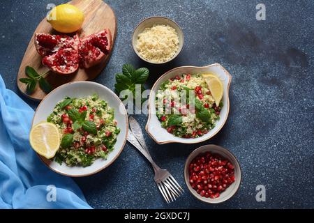 Gesunder Salat mit Couscous, frischer Minze, Gurke, Granatapfel, Zitrone und Olivenöl. Östliche Küche. Veganes Lebensmittelkonzept. Traditionelle israelische Küche Stockfoto