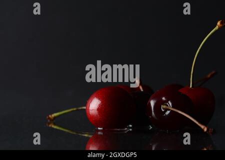 Kirschen, mit Wassertropfen auf schwarzem Hintergrund mit Spiegelung Stockfoto